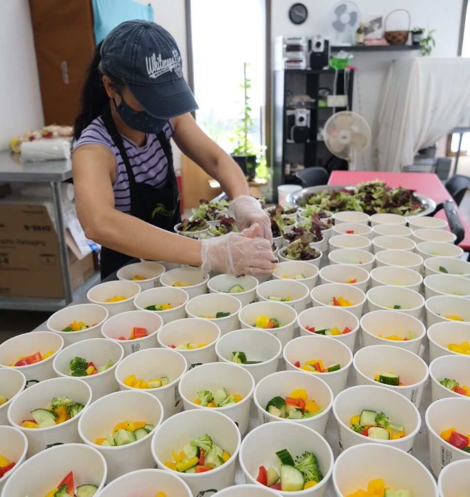 A person preparing salads into bowls