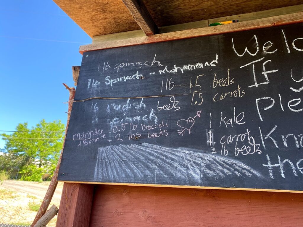 A chalkboard with names of produce and numbers scrawled indiscriminately on the side.